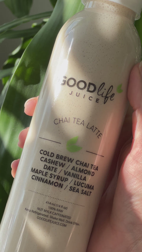 Video showing a Chai Tea Latte bottle being held in front of green leaves.